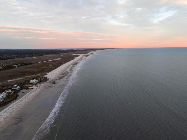 aerial view at dusk with a water view and a beach view