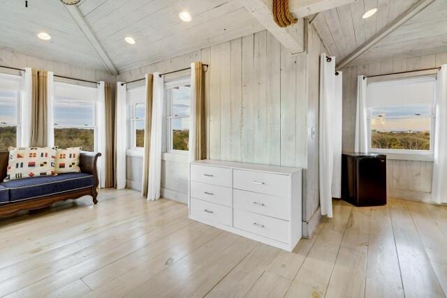 living area featuring lofted ceiling with beams, light hardwood / wood-style flooring, a wealth of natural light, and wood ceiling