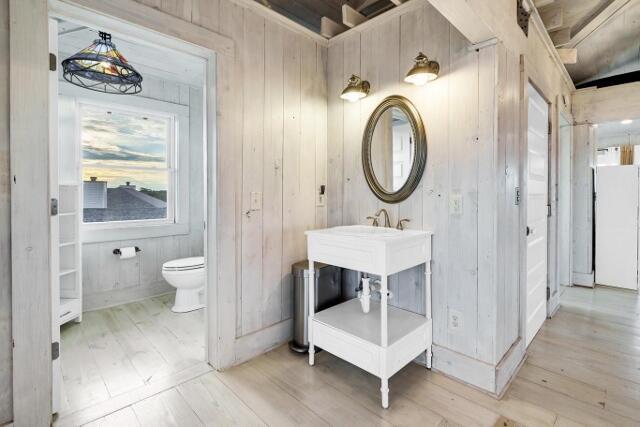 bathroom with hardwood / wood-style floors, toilet, and wood walls