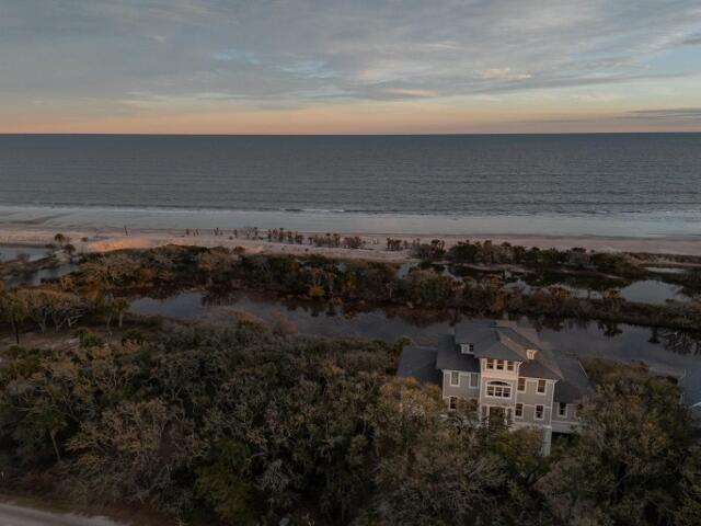 aerial view at dusk with a water view and a view of the beach