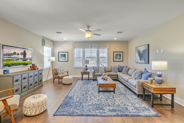 living area featuring visible vents, ceiling fan, baseboards, and wood finished floors