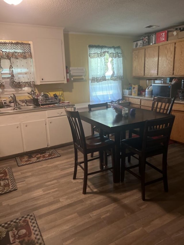 dining space with hardwood / wood-style floors, sink, and a textured ceiling