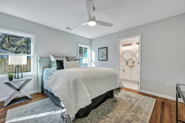 bedroom featuring a ceiling fan, wood finished floors, visible vents, baseboards, and connected bathroom