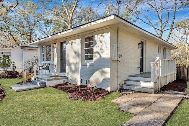 ranch-style home featuring brick siding, a front yard, and fence