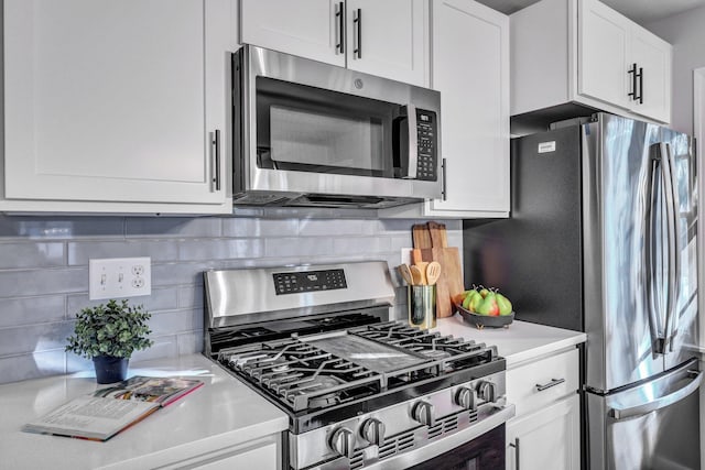 kitchen with stainless steel appliances, white cabinetry, backsplash, and light countertops