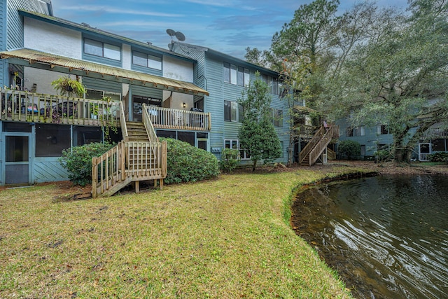 rear view of property with a yard, a water view, and a sunroom