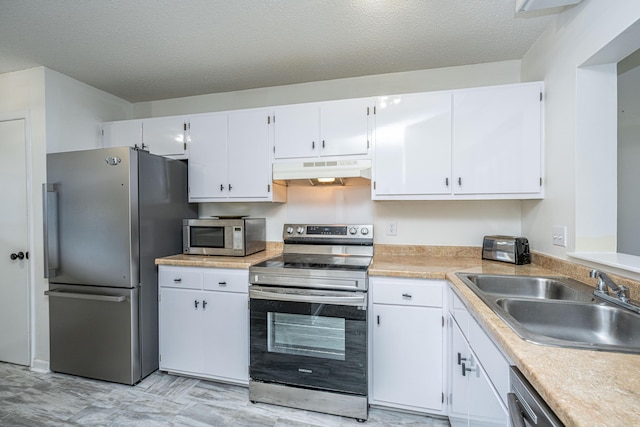 kitchen with appliances with stainless steel finishes, a textured ceiling, white cabinetry, and sink