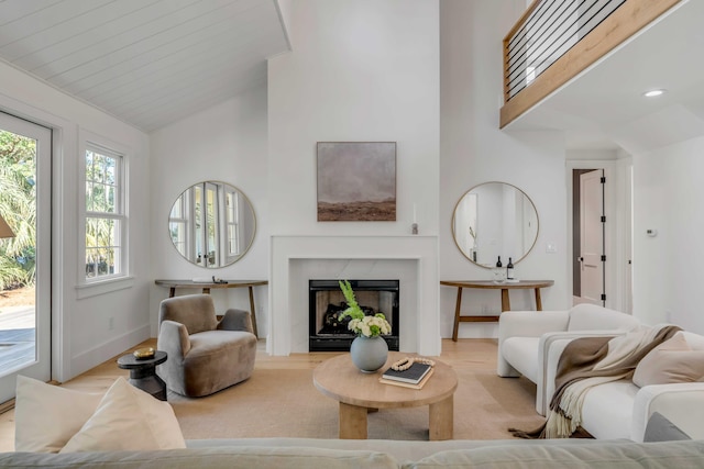 living area featuring high vaulted ceiling, baseboards, and a premium fireplace