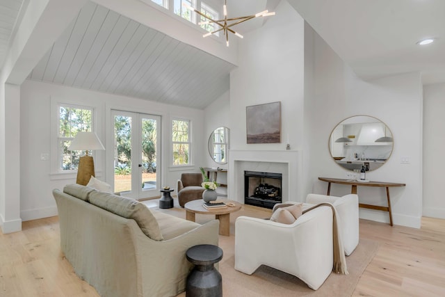 living area featuring french doors, a premium fireplace, light wood-type flooring, and baseboards