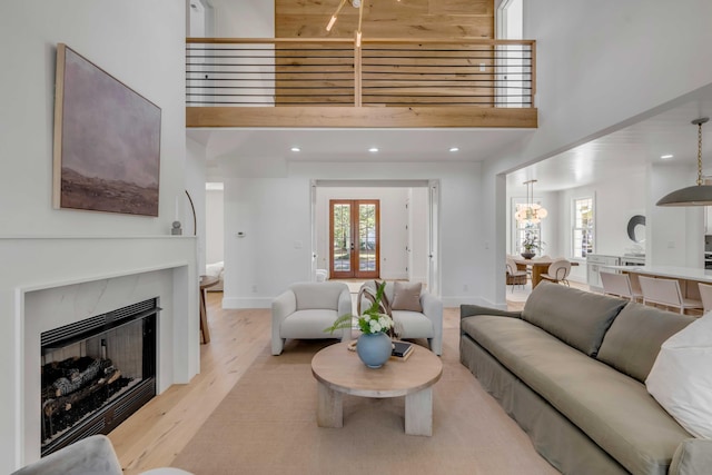 living room with light wood-style floors, a glass covered fireplace, a healthy amount of sunlight, and a high ceiling