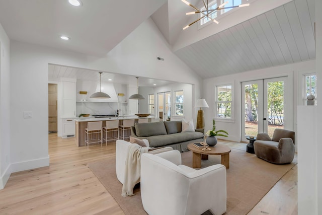 living room with light wood-style floors, french doors, high vaulted ceiling, and baseboards