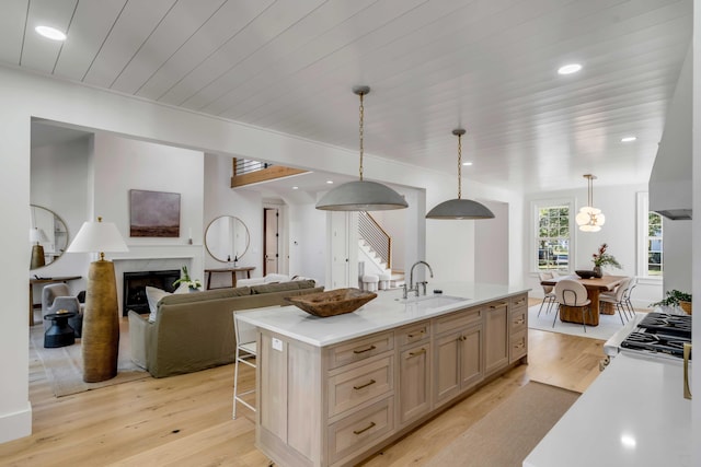 kitchen with light wood-style flooring, a premium fireplace, open floor plan, light countertops, and a sink