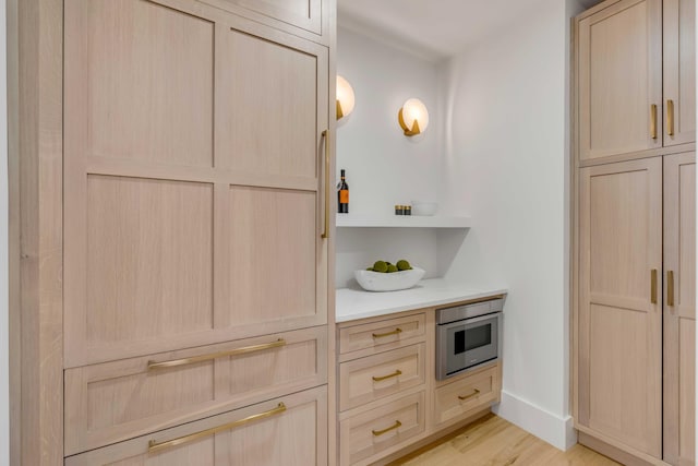 kitchen featuring light wood-style floors, light brown cabinets, baseboards, and light countertops