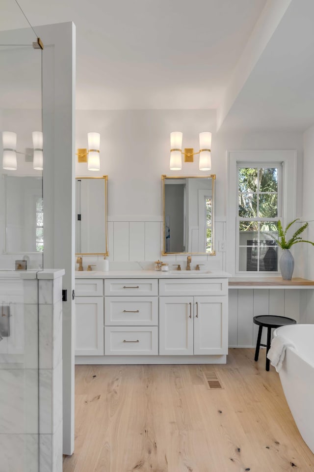 full bathroom with a freestanding bath, a shower, wood finished floors, and vanity