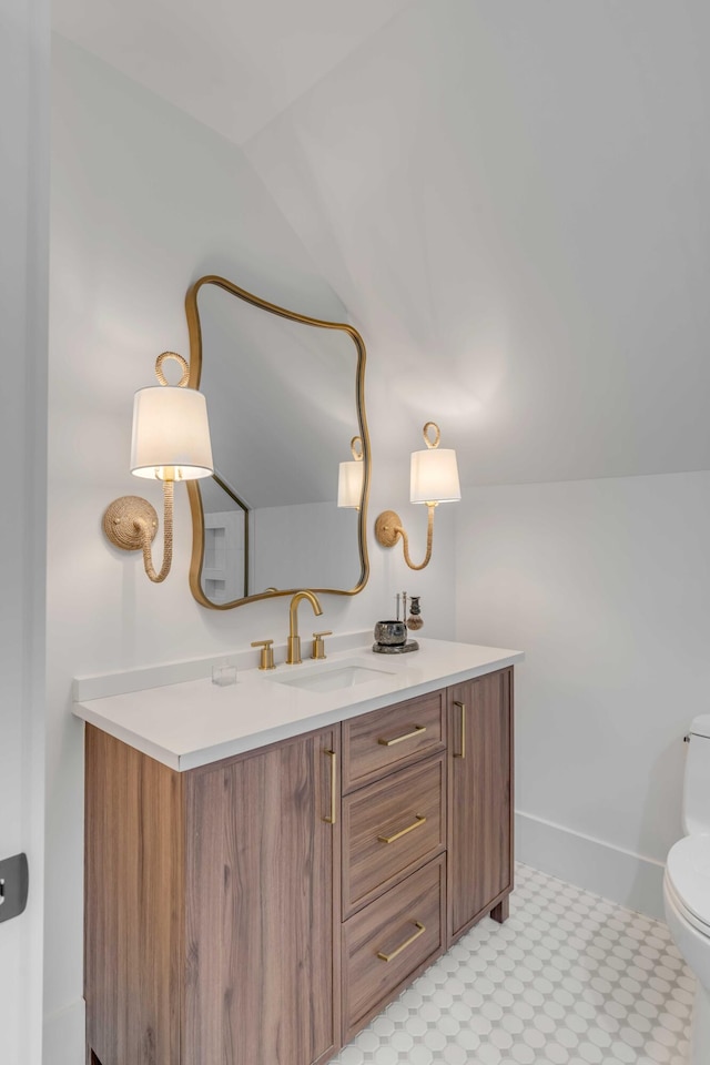 half bathroom with vanity, toilet, and baseboards