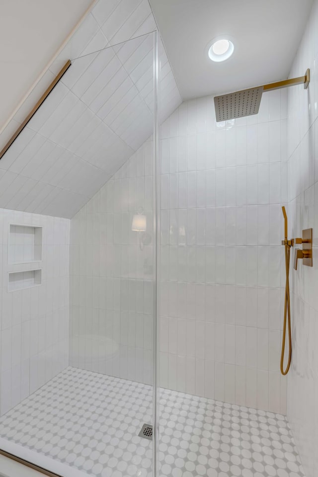 bathroom featuring lofted ceiling and tiled shower