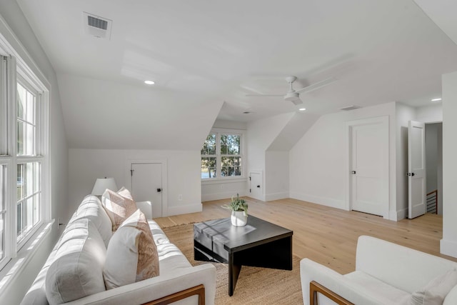 living room featuring light wood-type flooring, visible vents, vaulted ceiling, and baseboards