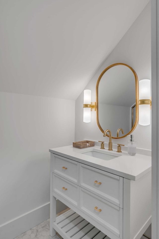 bathroom with lofted ceiling, baseboards, and vanity