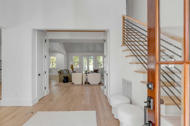 entryway with lofted ceiling, wood finished floors, visible vents, baseboards, and stairs