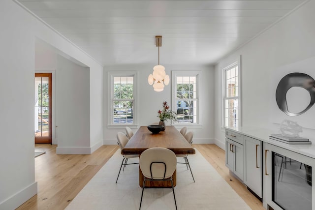 dining room featuring wine cooler, light wood-type flooring, and a wealth of natural light