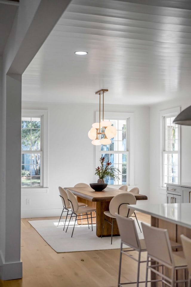 dining room with a healthy amount of sunlight, light wood-style flooring, and an inviting chandelier