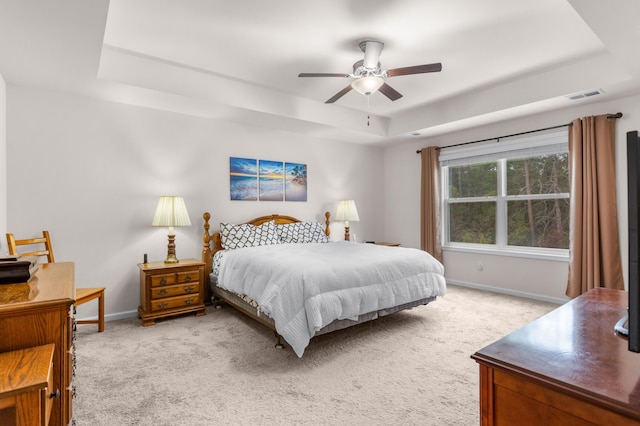 carpeted bedroom featuring ceiling fan and a raised ceiling