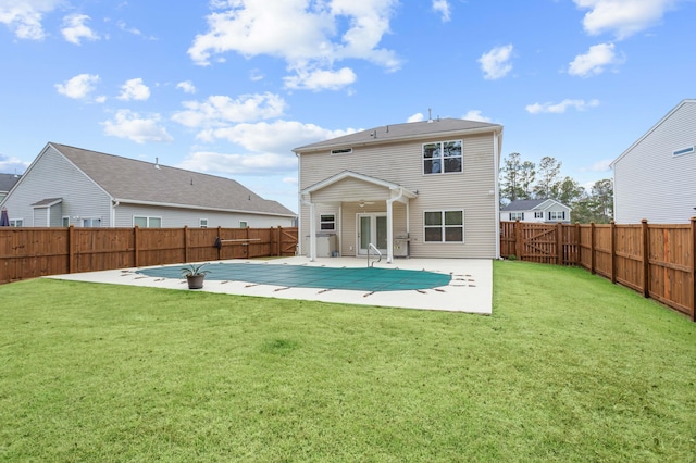 rear view of house featuring a lawn, a patio, and a covered pool