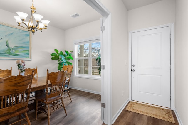 dining area with dark wood-type flooring and an inviting chandelier