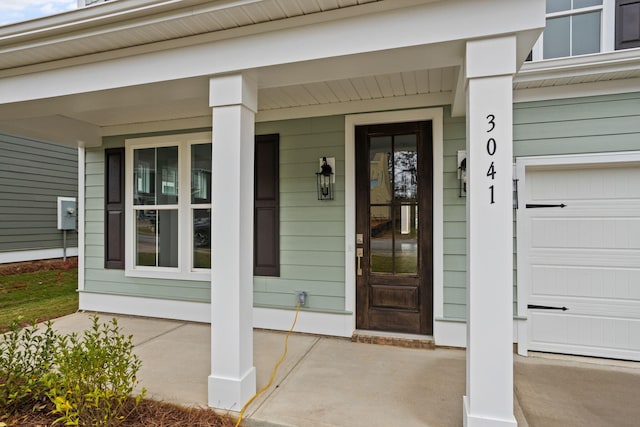 doorway to property with covered porch and a garage