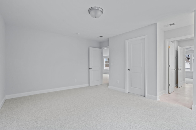 unfurnished bedroom with visible vents, baseboards, and light colored carpet