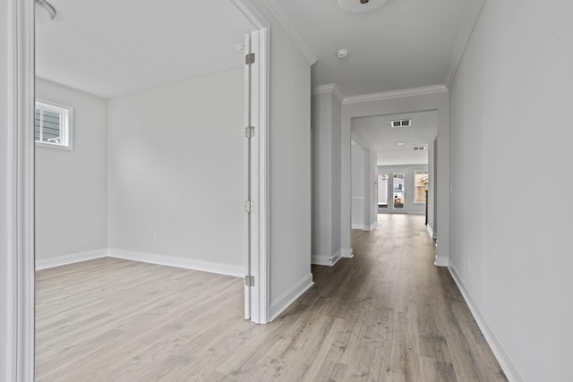 hallway featuring visible vents, light wood-style flooring, crown molding, and baseboards