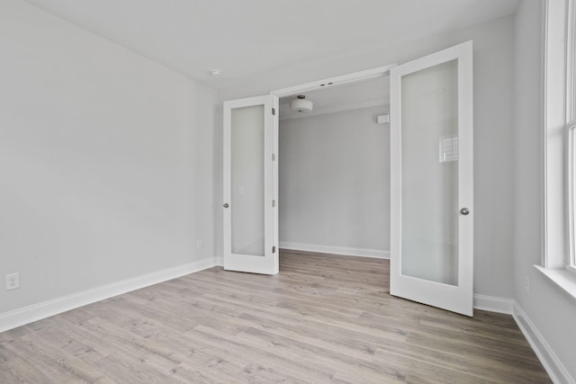 spare room with french doors, baseboards, and wood finished floors