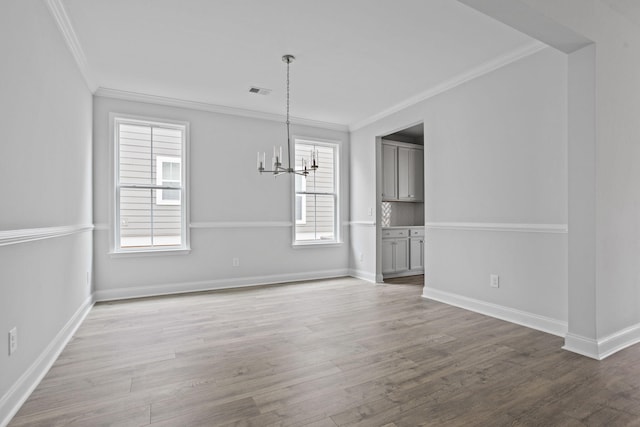 unfurnished dining area with visible vents, crown molding, baseboards, wood finished floors, and a notable chandelier