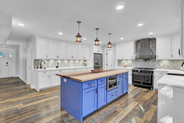 4429 Francis Younge Way, Hollywood, SC 29449 - kitchen with wall chimney range hood, blue cabinets, high end stove, stainless steel fridge, and butcher block countertops