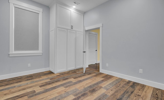 unfurnished bedroom featuring a closet and dark wood-type flooring