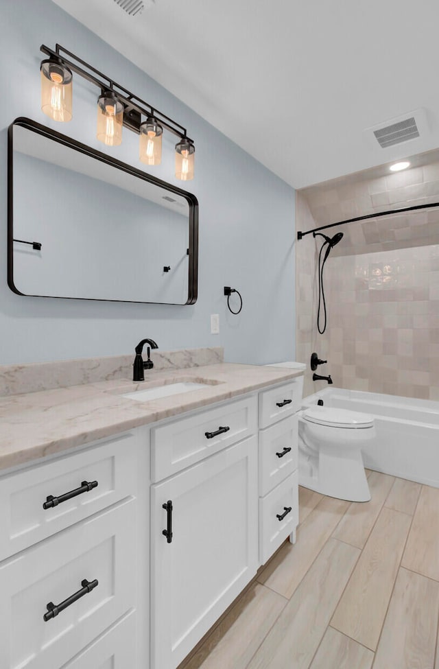 full bathroom with vanity, tiled shower / bath combo, toilet, and wood-type flooring