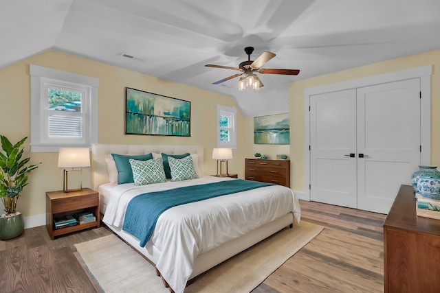 bedroom featuring lofted ceiling, a closet, wood-type flooring, and ceiling fan