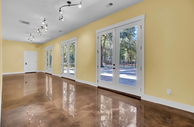 doorway to outside with french doors, rail lighting, a healthy amount of sunlight, and concrete floors