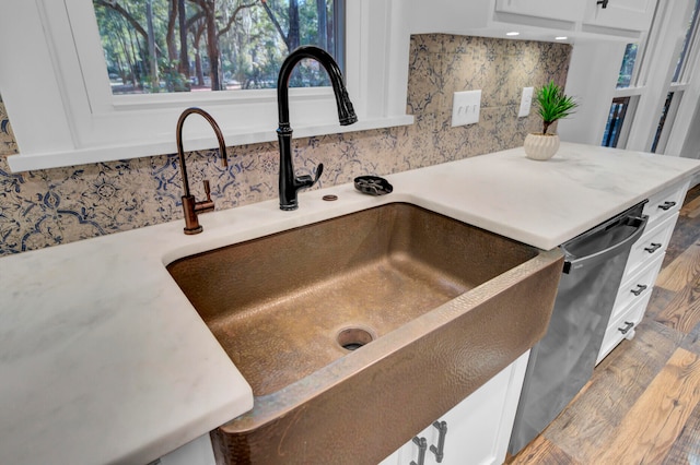 details with white cabinetry, stainless steel dishwasher, and sink