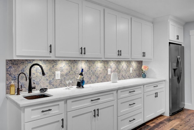 kitchen with tasteful backsplash, sink, stainless steel fridge, white cabinets, and dark wood-type flooring