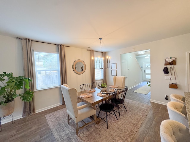 dining room featuring dark wood-type flooring, an inviting chandelier, and plenty of natural light