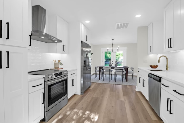 kitchen with stainless steel appliances, light countertops, visible vents, a sink, and wall chimney exhaust hood