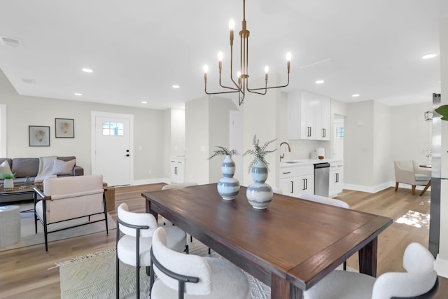 dining space featuring a chandelier, light wood-style flooring, visible vents, and baseboards