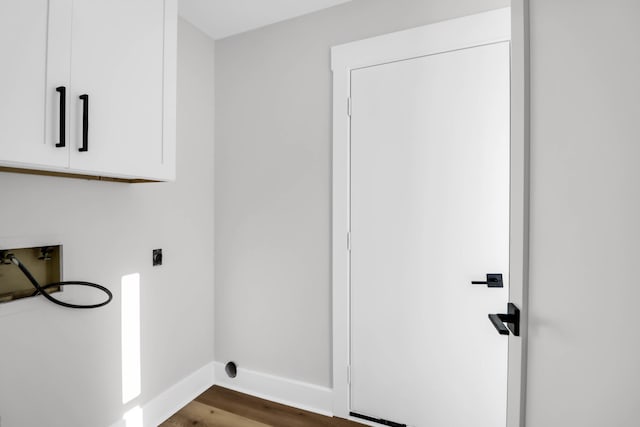 laundry room with hookup for an electric dryer, cabinet space, dark wood finished floors, baseboards, and washer hookup