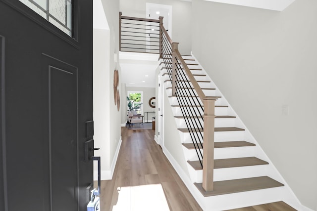 entryway featuring stairway, a high ceiling, baseboards, and light wood-type flooring