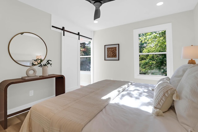 bedroom with baseboards, wood finished floors, recessed lighting, and a barn door