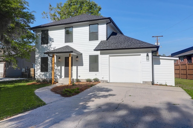 traditional-style house with a garage, concrete driveway, a shingled roof, fence, and a front yard