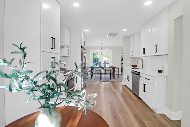 kitchen featuring stainless steel appliances, visible vents, light wood-style floors, white cabinetry, and light countertops