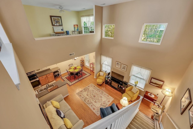 living room with a towering ceiling, hardwood / wood-style floors, and ceiling fan