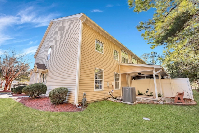 view of side of property with a yard, ceiling fan, and central AC